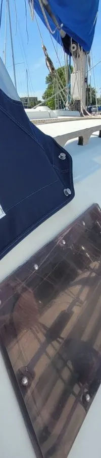 Een deel van een zeilboot met een blauwe huik, ramen en een reling, liggend in een haven. — Feeling 346