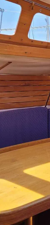 De foto toont een kajuit met houten wanden en plafond, blauwe kussens en een houten tafel. — Feeling 346