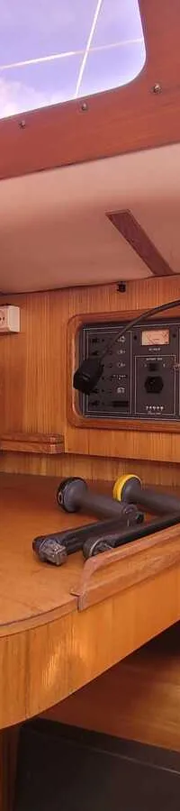 Een houten interieur van een boot met een navigatiehoek, Raymarine-apparatuur, een luidspreker en diverse meters.
