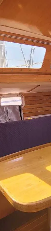 De foto toont de kajuit van een boot met houten wanden en plafond, een houten tafel en paarse banken. — Feeling 346