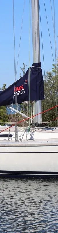 Een witte zeilboot met een blauwe zeilhoes en een beige buiskap vaart op rustig water. — Luffe 46
