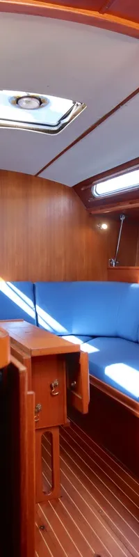 De foto toont het interieur van een boot met houten wanden en vloer, een blauwe bank, een gootsteen en diverse instrumenten.
