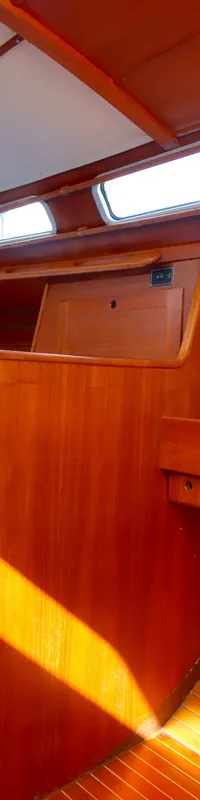 De foto toont het interieur van een boot met houten wanden, een blauwe bank, een klaptafel en een navigatiepaneel. — Luffe 46