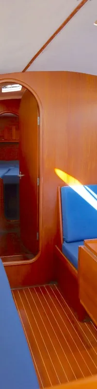 De foto toont het interieur van een boot met houten wanden, blauwe banken, een houten tafel en ramen. — Luffe 46