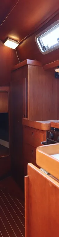 De foto toont een houten kajuitinterieur met een kombuis, inclusief een gootsteen en een kooktoestel.