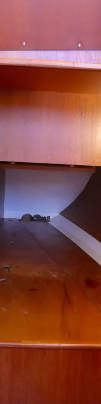 Een houten interieur van een boot met een open opbergruimte, een haakje aan de wand en een wit koord. — Luffe 46