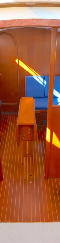 De foto toont het interieur van een boot met houten wanden en vloer, een gootsteen, en blauwe banken. — Luffe 46