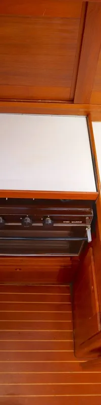 Een kombuis met een roestvrijstalen spoelbak, een kraan, een fornuis met oven en houten kasten.