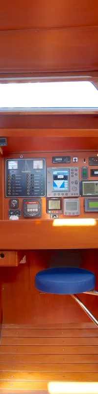De foto toont een houten interieur van een boot met een navigatiehoek, een blauwe bank en een deur. — Luffe 46
