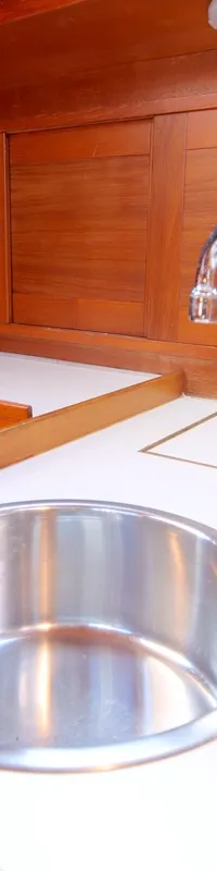 Een kombuis met een roestvrijstalen spoelbak, een kraan, een fornuis en houten kasten.