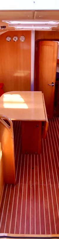 De kajuit van een boot met houten interieur, blauwe banken, een tafel en een gootsteen. — Bavaria 31