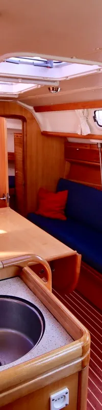 De foto toont een houten interieur van een boot met een kombuis, zithoek en navigatiehoek. — Bavaria 31