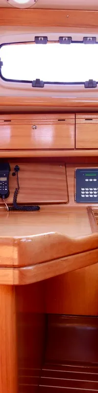 De foto toont een houten interieur van een boot met een navigatietafel, een paneel met knoppen en een telefoon. — Bavaria 31