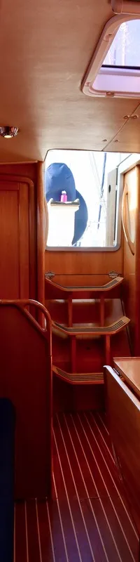 De foto toont het interieur van een boot met houten afwerking, blauwe kussens, een tafel en een kombuis. — Bavaria 31
