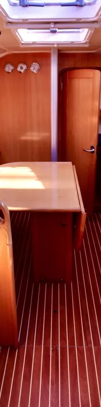 De foto toont het interieur van een boot met houten afwerking, blauwe banken, een tafel en een kombuis met spoelbak.