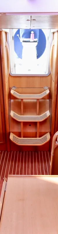 De foto toont het interieur van een boot met houten afwerking, blauwe kussens, een kombuis en een navigatiehoek. — Bavaria 31