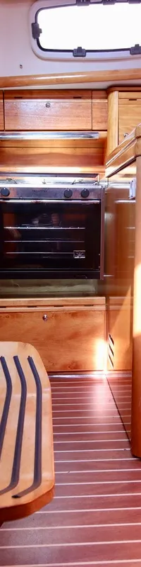 De foto toont een houten interieur van een boot met een trap, kombuis en ramen. — Bavaria 31