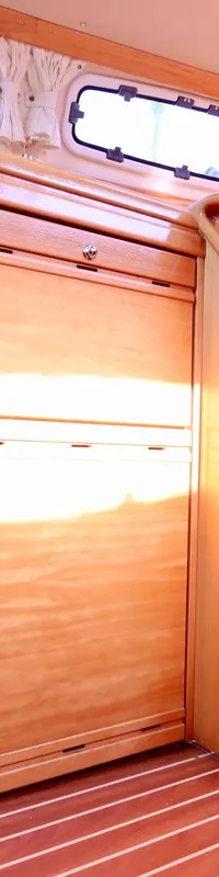 De foto toont het interieur van een boot met een oven, houten kasten, een tafel en een blauwe bank. — Bavaria 31