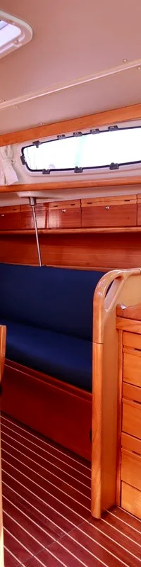 De foto toont het interieur van een boot met een kombuis, zithoek en navigatiehoek, alles afgewerkt met hout. — Bavaria 31