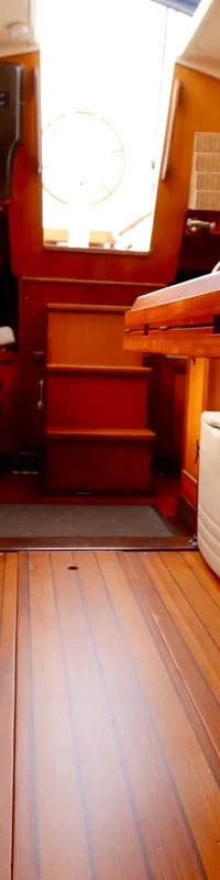 De kajuit van een boot is zichtbaar, met een houten interieur, gestoffeerde banken en een tafel in het midden.