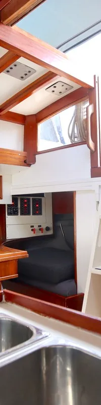 Een interieur van een boot met houten afwerking, een gootsteen op de voorgrond en een witte trap aan de rechterkant.