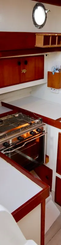 De foto toont een kombuis met een fornuis, twee spoelbakken, houten kasten en een brandblusser.