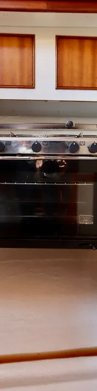 De foto toont een kombuis met een fornuis en oven, omringd door houten kasten en panelen.