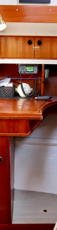 De foto toont een kajuit met een houten bureau, een trap en een deur met een messing handvat. — Colin Archer Polar 34