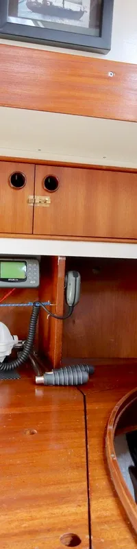 De foto toont een interieur van een boot met houten afwerking, een bed met zwart kussen, en diverse apparatuur.