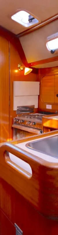 De foto toont het interieur van een boot met een houten trap, een kombuis met dubbele spoelbak en een fornuis. — Bavaria 38