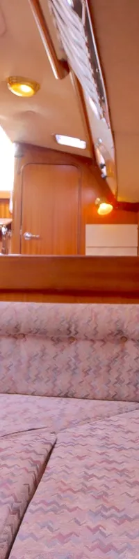 De foto toont het interieur van een boot met houten wanden, een bank met stoffen bekleding en een olielamp. — Bavaria 38