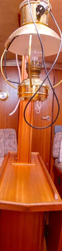 De foto toont het interieur van een kajuit met houten wanden, twee banken met gestoffeerde kussens en een centrale tafel.