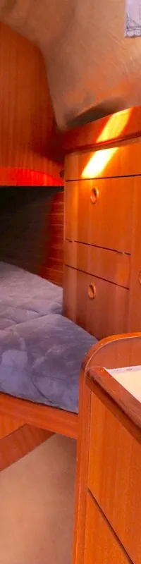 De foto toont een kajuit met een bed, houten kasten, een leeslampje en een witte wasbak. — Bavaria 38