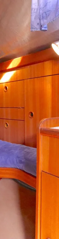 De foto toont een kajuit met een bed met blauw dekbed, houten kasten en een wasbak met kraan. — Bavaria 38