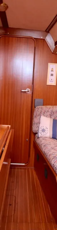Een interieur van een boot met houten wanden, vloer en meubilair, twee banken met gestoffeerde kussens en een kussen met…