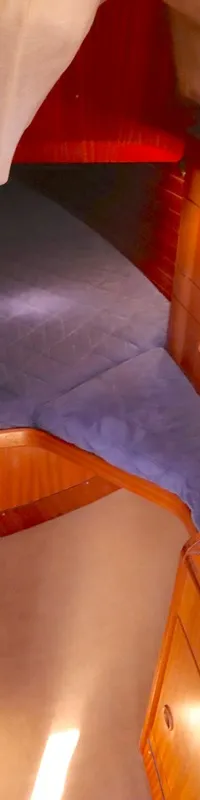 De foto toont een interieur van een boot met een bed, een wasbak en houten kasten en wanden. — Bavaria 38