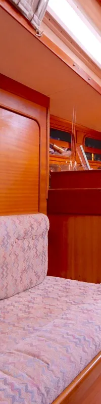 De foto toont het interieur van een boot met houten wanden, een bank met stoffen bekleding en een televisie. — Bavaria 38
