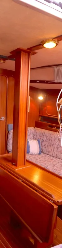 De foto toont het interieur van een boot met houten wanden, banken met gestoffeerde kussens en een hangende olielamp.