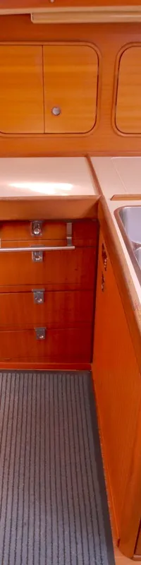 Een kombuis met een fornuis, oven, dubbele spoelbak, houten kasten en een bank met kussens.