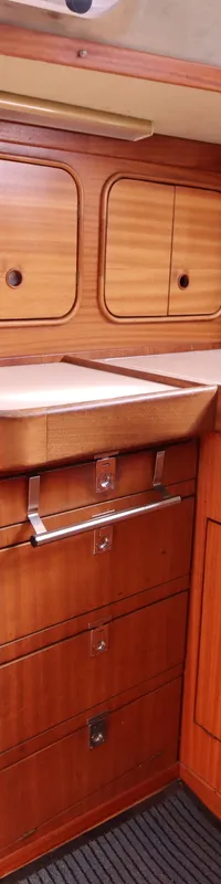 Een houten scheepsinterieur met een fornuis, oven, gootsteen en opbergkasten.