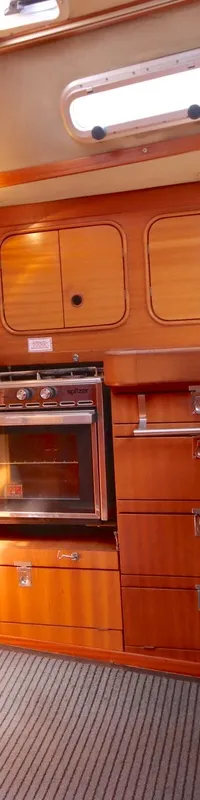 De foto toont een houten interieur van een boot met een kombuis, trap en ramen. — Bavaria 38
