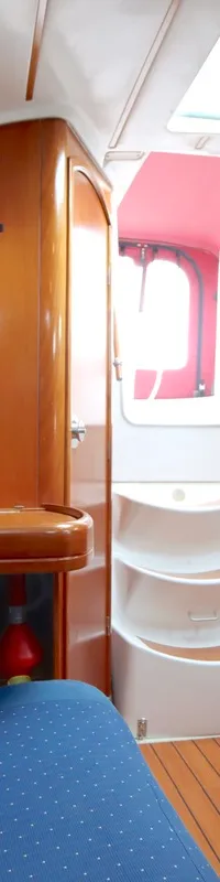 De foto toont het interieur van een boot met houten wanden, een blauwe gestippelde bank, een gootsteen en een trap.