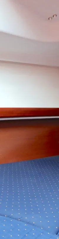 De foto toont een kajuit met een blauw gestippeld matras, houten wanden en een wit plafond. — Beneteau Oceanis 311 Clipper