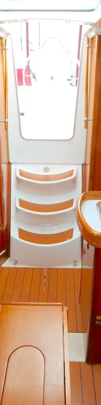 De foto toont het interieur van een boot met houten wanden, blauwe zitbanken en een kombuis. — Beneteau Oceanis 311 Clipper