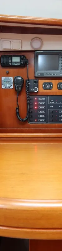 Een houten navigatiehoek met een blauwe gestippelde bank, diverse elektronica en een schakelpaneel.