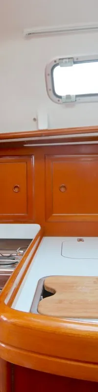 Een kombuis met een fornuis, oven, gootsteen, houten aanrechtblad en een blauw gordijn bij een raam.