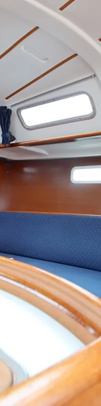De foto toont het interieur van een boot met houten afwerking, blauwe kussens, een gootsteen en navigatieapparatuur.