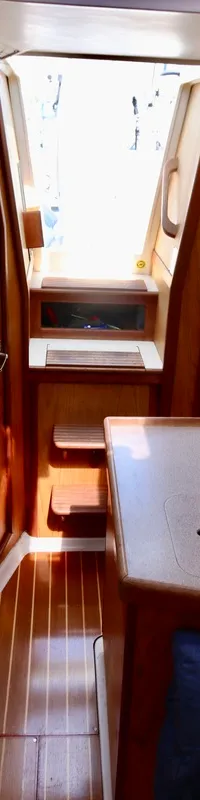 Een interieur van een boot met houten wanden en vloer, een kombuis met dubbele spoelbak en een brandblusser aan de muur.