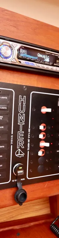 Een houten paneel met diverse meters, schakelaars, een radio, een telefoon en een stopcontact.