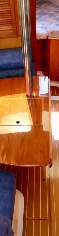 De foto toont een interieur van een boot met houten wanden en vloer, blauwe banken en een houten tafel. — Hunter 340
